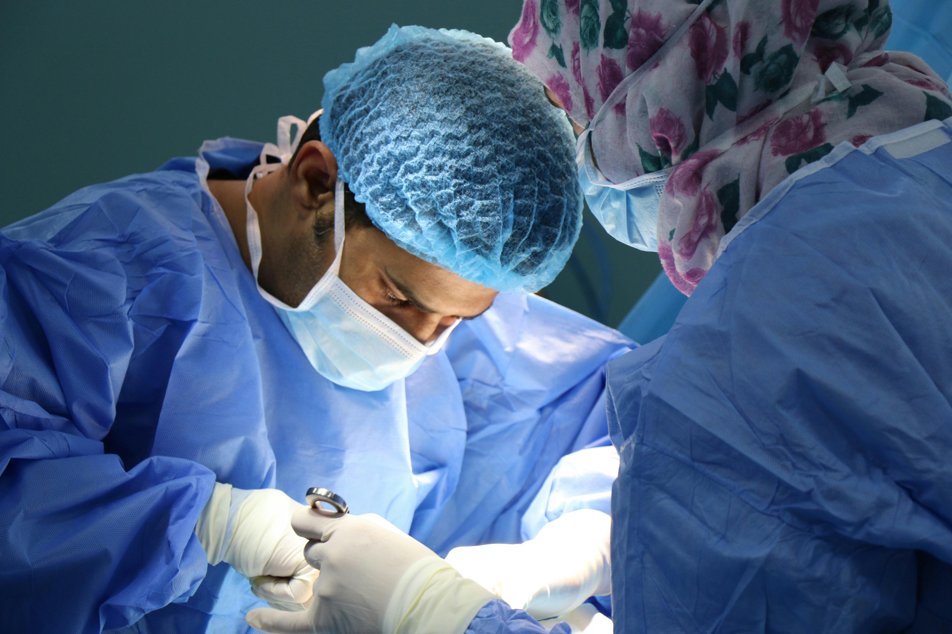 Surgeons in scrubs and caps operating